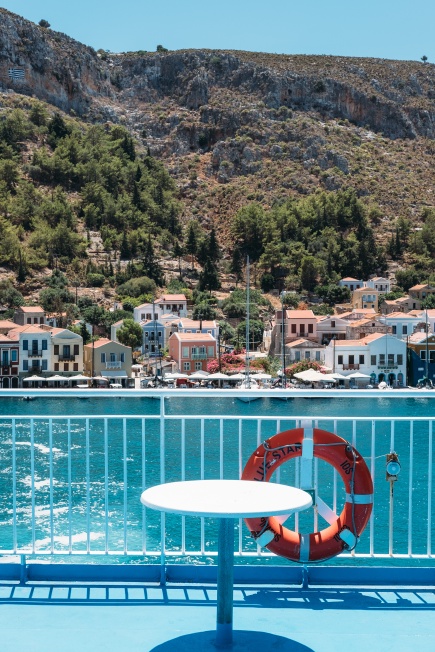 A photo of houses on a bay with elements of a ferry deck in the foreground