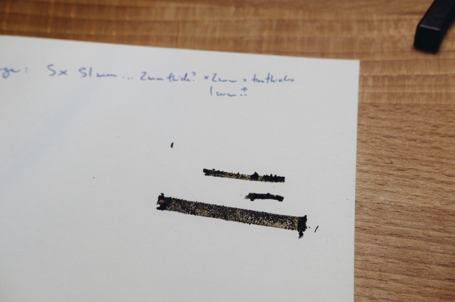 Three strips of decayed light seal foam stuck to a piece of paper