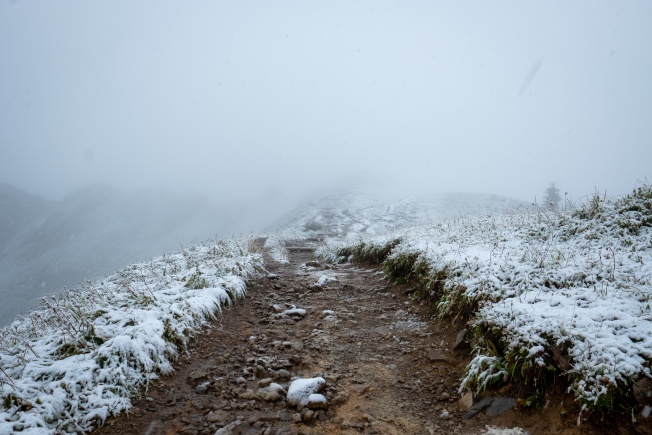 A muddy trail with fresh snow on the edges