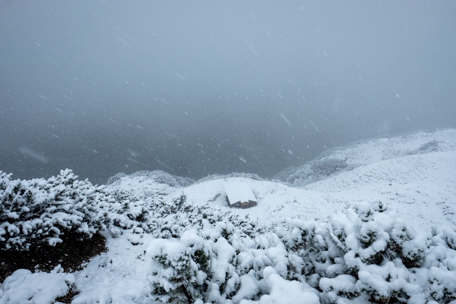 A hut on the side of a mountain, half-buried in snow.