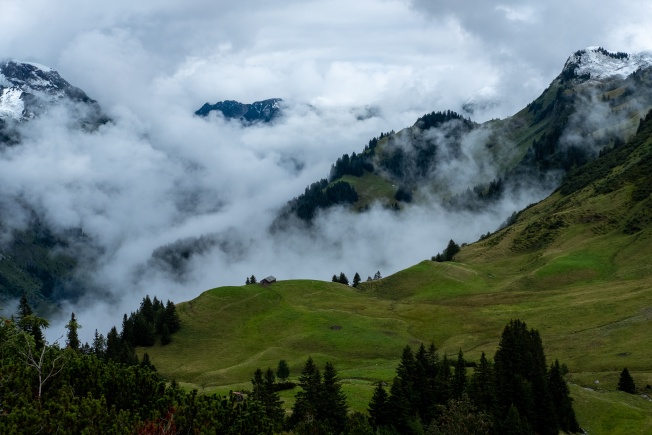 A hut in a valley in the alps. Low cloud everywhere.