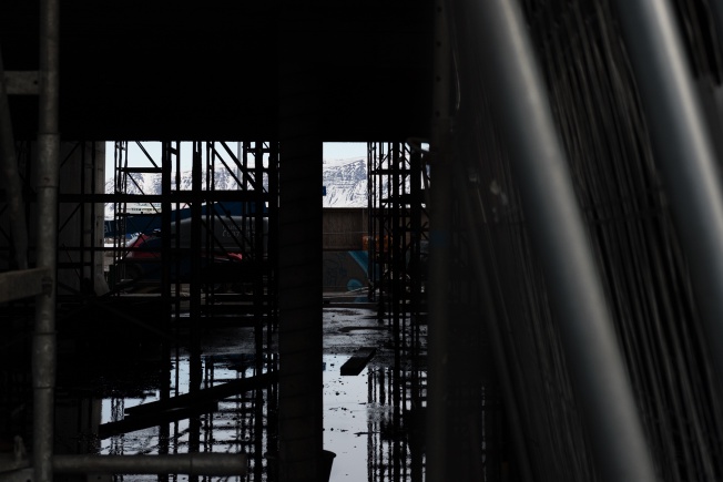 a construction site with a snow-capped mountain visible through a gap in the girders