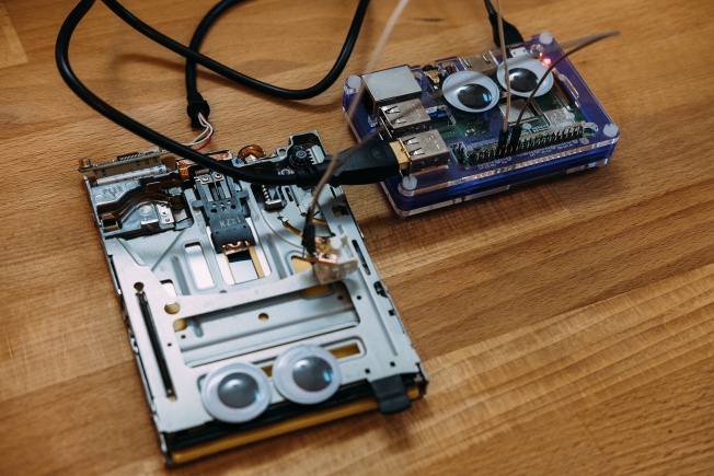 The floppy disk drive is connected to the Raspberry Pi via GPIO. The Raspberry Pi also has googly eyes.